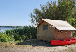 Tienda safari en Marina Parcs Almere, Países Bajos, junto al lago y con una canoa roja frente a la tienda.