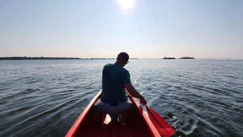 Person i en rød båd på vandet under solen, taget fra Safari-telt ved Marina Parcs Almere i Holland.