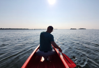 Person in einem roten Boot auf dem Wasser bei Sonnenlicht, fotografiert beim Safari-Zelt in Marina Parcs Almere.