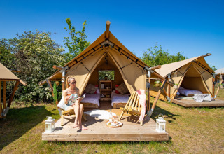 Mujer relajándose frente a tiendas safari en Marina Parcs Almere, Países Bajos, en un día soleado.