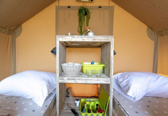 Interno di una tenda safari a Marina Parcs Almere con due letti singoli e utensili da cucina.