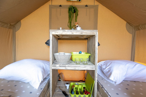 Intérieur d'une tente safari à Marina Parcs Almere avec deux lits simples et des ustensiles de cuisine.