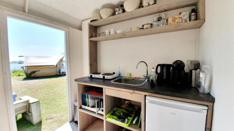 Compact kitchenette inside a safari tent at Marina Parcs Almere, Netherlands, with outdoor tent view.
