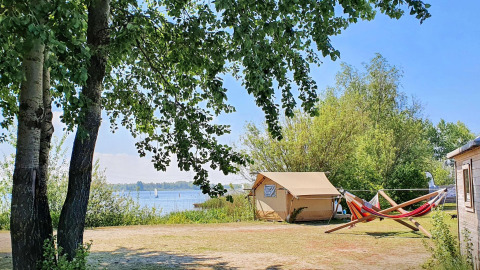 Tienda safari en Marina Parcs Almere, Países Bajos, con vistas al lago, hamacas y árboles alrededor.