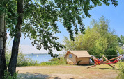 Safari-Zelt bei Marina Parcs Almere in den Niederlanden mit Blick auf den See, Hängematten und Bäumen.