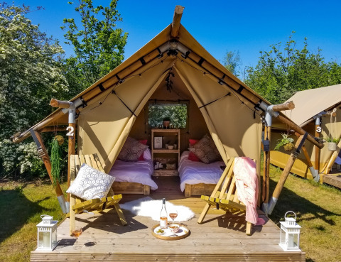 Tente safari à Marina Parcs Almere aux Pays-Bas, deux lits, chaises en bois et espace pique-nique chaleureux.