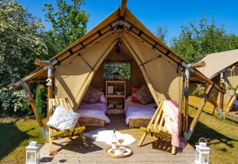Safari-telt ved Marina Parcs Almere i Holland med to senge, stole og udendørs picnicområde under solen.