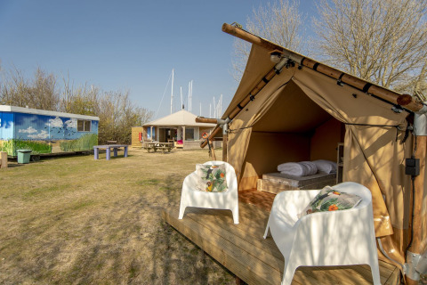 Tienda safari en Marina Parcs Almere, Países Bajos, con dos sillas y vista a espacios de camping compartidos.