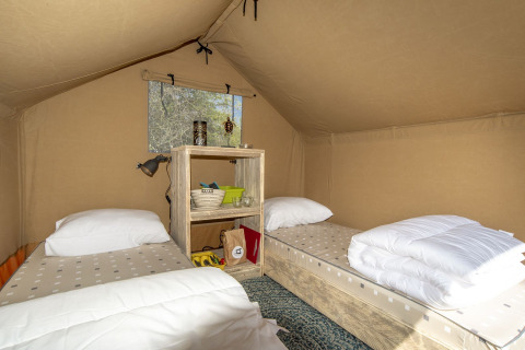 Indretning af Safari telt ved Marina Parcs Almere i Holland med to enkeltsenge og hylde mellem dem.
