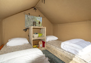 Interior of a safari tent at Marina Parcs Almere, Netherlands, featuring two single beds and shelving.