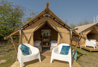 Tienda safari en Marina Parcs Almere, Países Bajos, con dos sillas blancas y cojines azules en la terraza.