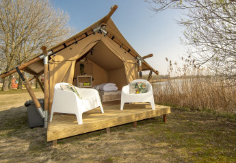 Safari-Zelt bei Marina Parcs Almere in den Niederlanden mit zwei weißen Stühlen auf einer Holzterrasse am Wasser.