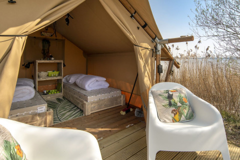 Innenaufnahme eines Safarizelts mit zwei Betten und Stühlen bei Marina Parcs Almere in den Niederlanden.