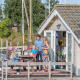 En familie nyder solen udenfor deres chalet ved Marina Parcs Almere i Holland, med både i baggrunden.