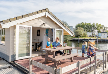 Family enjoys time on the terrace of a chalet at Marina Parcs Almere in the Netherlands, overlooking the water.