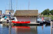 Canoa rossa vicino al molo accanto a un piccolo chalet ai Chalets at Marina Parcs Almere, Paesi Bassi.