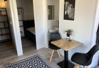 Modern lodge interior at Chalets at Marina Parcs Almere featuring dining table, black chairs, and zebra wall art.