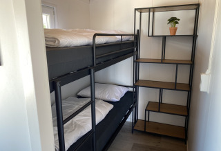 Habitación pequeña con litera y estantería con planta, en Chalets at Marina Parcs Almere, Países Bajos.