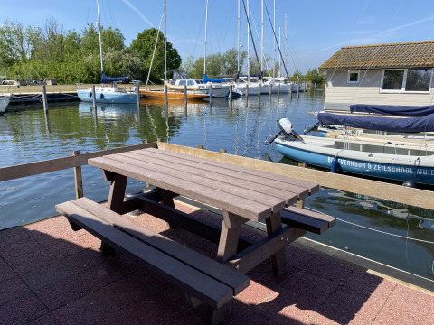 Outdoor picnic table by the marina with sailboats and cabins at Chalets at Marina Parcs Almere, Netherlands.