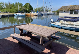 Outdoor picnic table by the marina with sailboats and cabins at Chalets at Marina Parcs Almere, Netherlands.