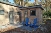 Area esterna del Forest park chalet 8p all’Holiday park De Kleine Belties con due sedie blu.