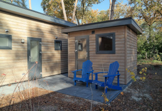 Area esterna del Forest park chalet 8p all’Holiday park De Kleine Belties con due sedie blu.