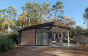 Modernes Forest park chalet 8p auf dem Holiday Park De Kleine Belties, umgeben von Bäumen und Natur.
