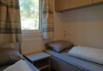Habitación con dos camas individuales y ropa de cama gris en Forest park chalet 8p, Países Bajos.