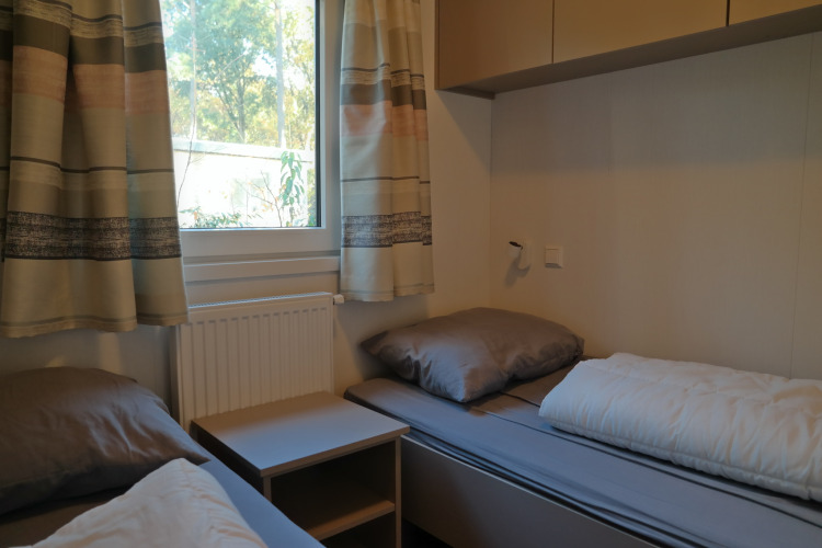 Habitación con dos camas individuales y ropa de cama gris en Forest park chalet 8p, Países Bajos.