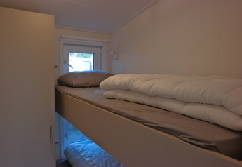 Sleeping area with bunk beds and a window in Forest park chalet 8p at Holiday park De Kleine Belties, Netherlands.