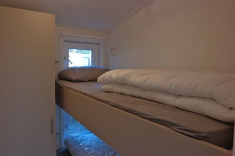 Sleeping area with bunk beds and a window in Forest park chalet 8p at Holiday park De Kleine Belties, Netherlands.
