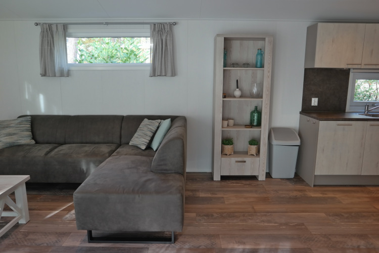 Sala del Forest park chalet 8p en Holiday park De Kleine Belties con sofá, estantería y cocina moderna.