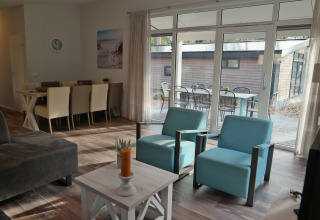 Stue i Forest park chalet 8p, De Kleine Belties, Holland, med moderne møbler og udsigt til terrasse.