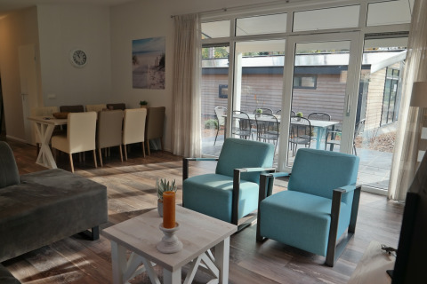 Stue i Forest park chalet 8p, De Kleine Belties, Holland, med moderne møbler og udsigt til terrasse.