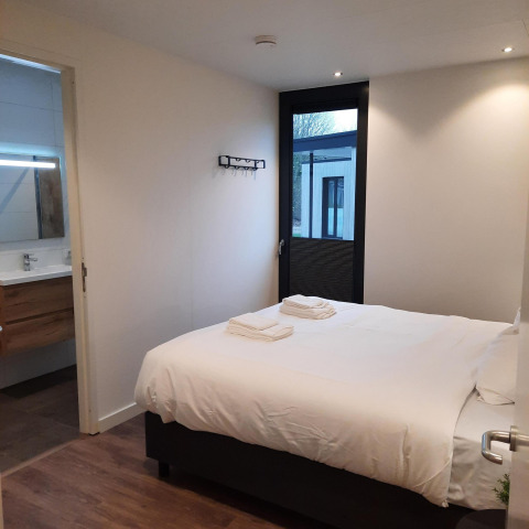 Dormitorio moderno en Forest Cube, Holiday Park BreeBronne, Países Bajos, con cama doble y baño privado.
