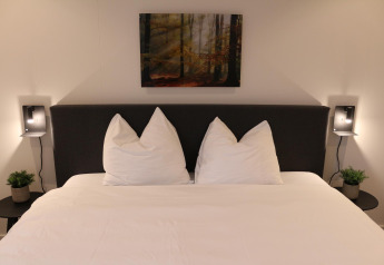 Letto moderno con lenzuola bianche, comodini e lampade a muro al Forest Cube, Holiday Park BreeBronne, Paesi Bassi.