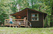 Familia disfruta al aire libre frente a una tienda safari en Youpi! Lodge de Beerze Bulten, Países Bajos.