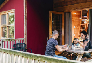 Familia sentada en la terraza de una tienda safari Youpi! Lodge en Beerze Bulten, Países Bajos, compartiendo bebidas.
