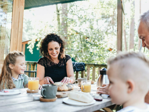Familie nyder morgenmad på terrassen ved en safariteltyoupi! Lodge på Beerze Bulten, Holland.