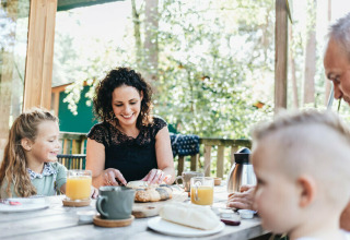 Familie nyder morgenmad på terrassen ved en safariteltyoupi! Lodge på Beerze Bulten, Holland.