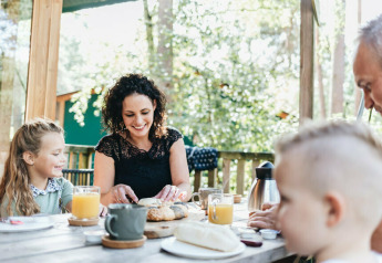 Familie nyder morgenmad på terrassen ved en safariteltyoupi! Lodge på Beerze Bulten, Holland.