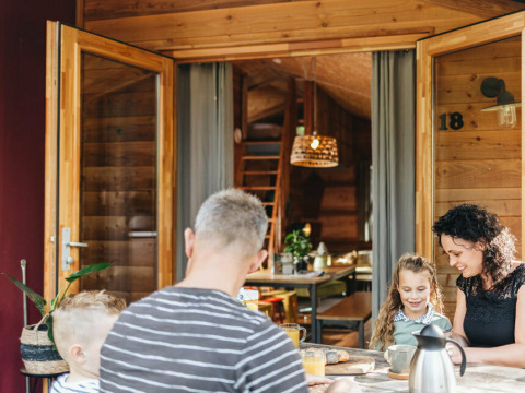 Familie nyder morgenmad udenfor en safaritelt ved Youpi! Lodge på Beerze Bulten, Holland.