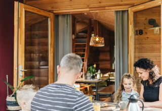 Familie nyder morgenmad udenfor en safaritelt ved Youpi! Lodge på Beerze Bulten, Holland.