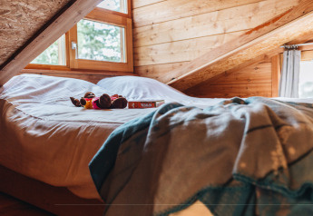 Cama acogedora con juguete y libro en un ático de madera en Youpi! Lodge, Beerze Bulten, Países Bajos.
