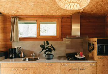 Cucina moderna in legno nella Youpi! Lodge a Beerze Bulten, Paesi Bassi, con finestra, pianta e accessori.