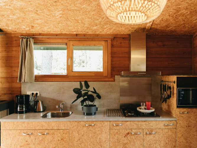 Modern wooden kitchen in Youpi! Lodge at Beerze Bulten, Netherlands, with window, plant and appliances.