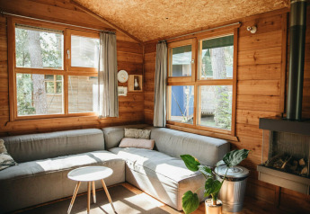 Acogedora sala en lodge tipo safari con sofá esquinero y ventanas grandes en Beerze Bulten, Países Bajos.