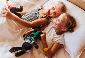 Due bambini felici ridono e giocano a letto in una tenda safari presso Youpi! Lodge a Beerze Bulten, Paesi Bassi.