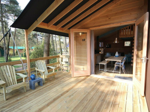 Veranda abierta con suelo de madera y sillas, entrada a Youpi! Lodge safari en Beerze Bulten, Países Bajos.