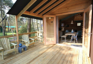 Véranda ouverte avec terrasse en bois et chaises, menant au Youpi! Lodge safari à Beerze Bulten, Pays-Bas.